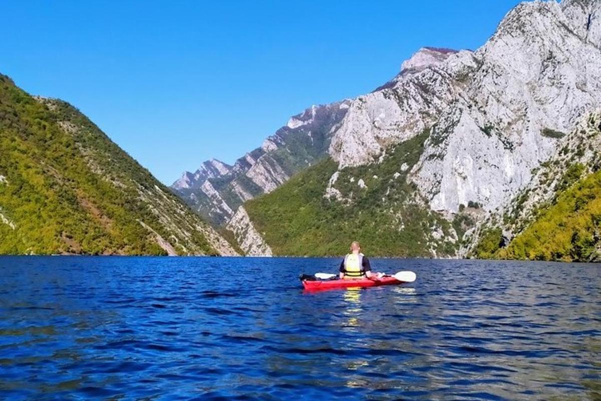 seseorang di kayak di danau di depan pegunungan