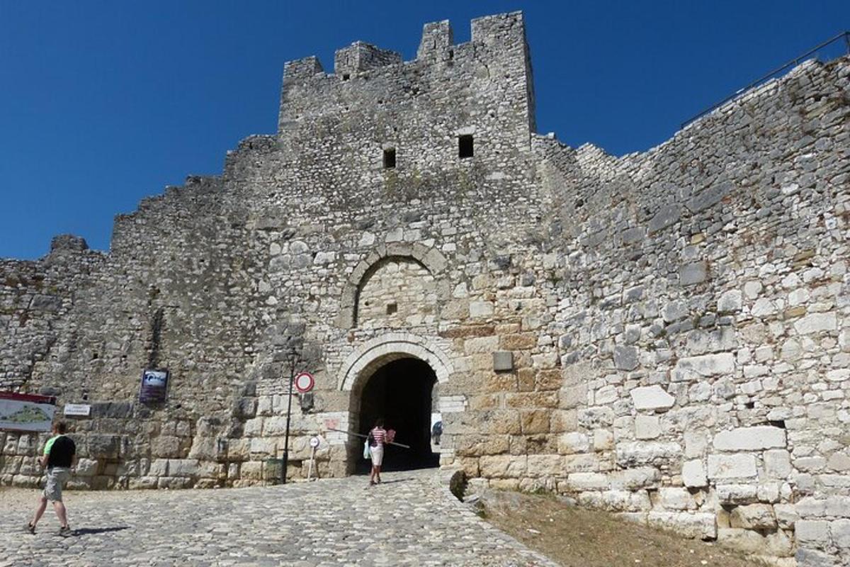 two people standing outside of a large castle
