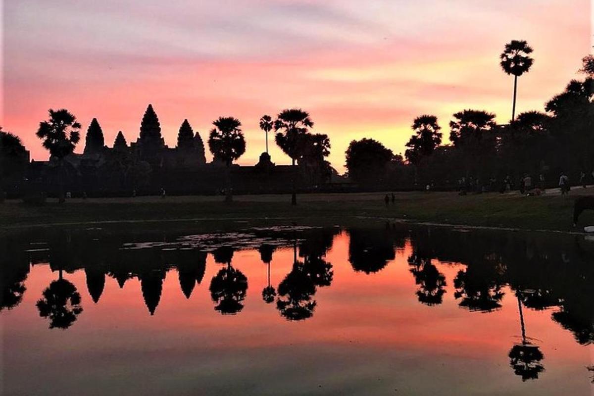 a sunset over a pond in front of a temple