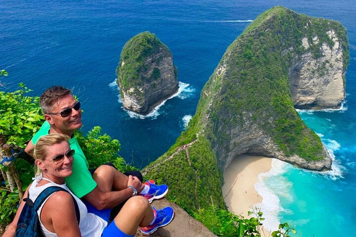 Dos personas sentadas en una roca con vistas al océano.