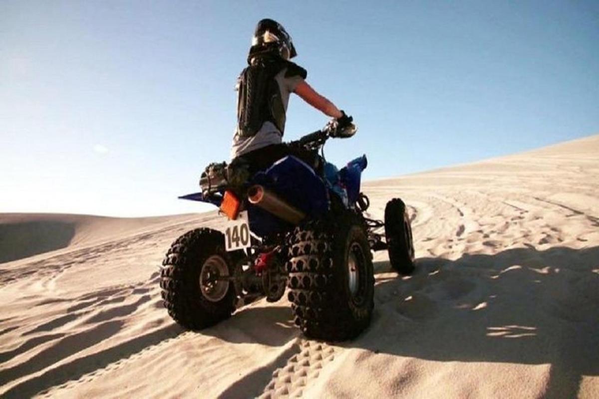 una persona que condueix un quad al desert