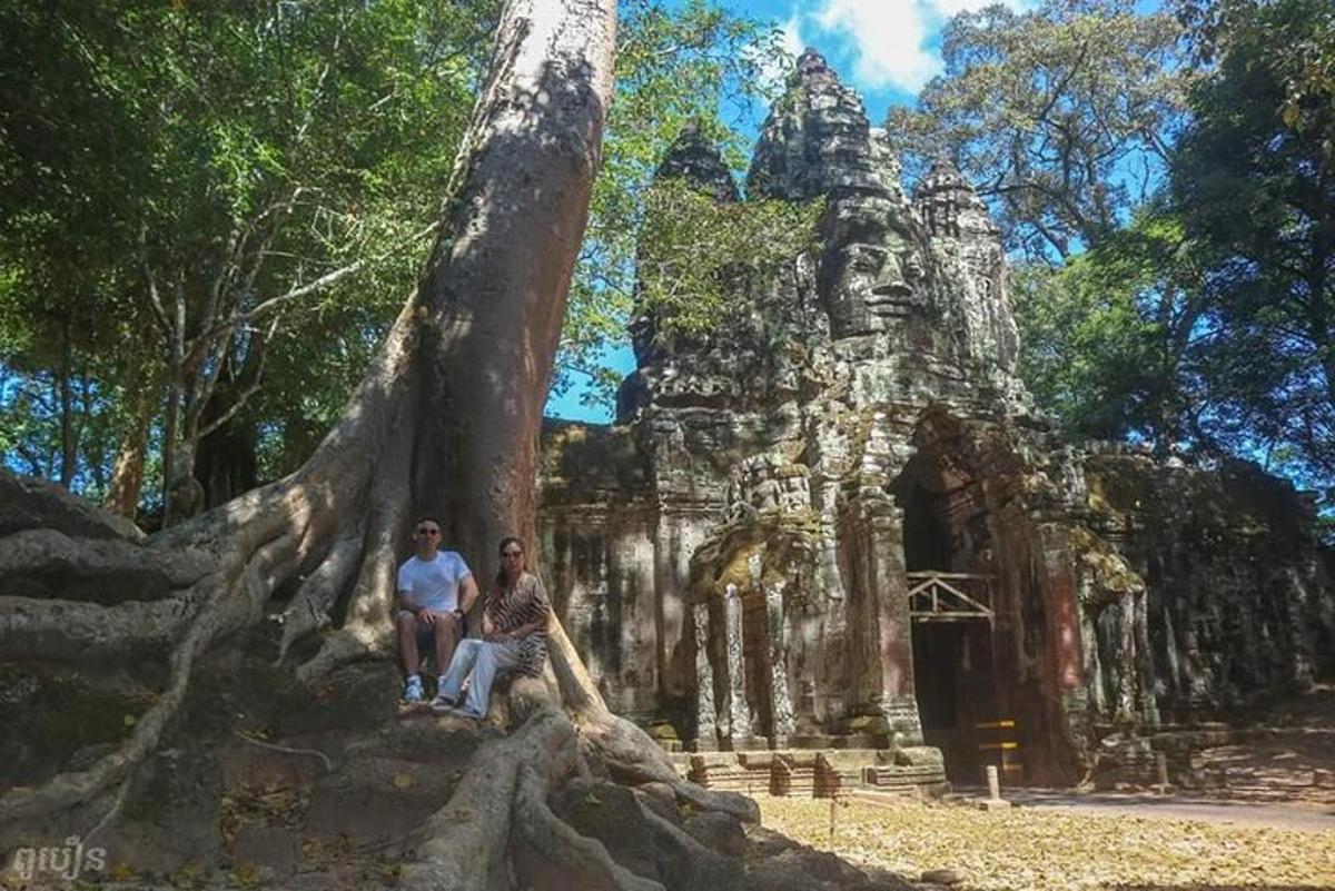 Dos personas de pie junto a un árbol frente a un templo.