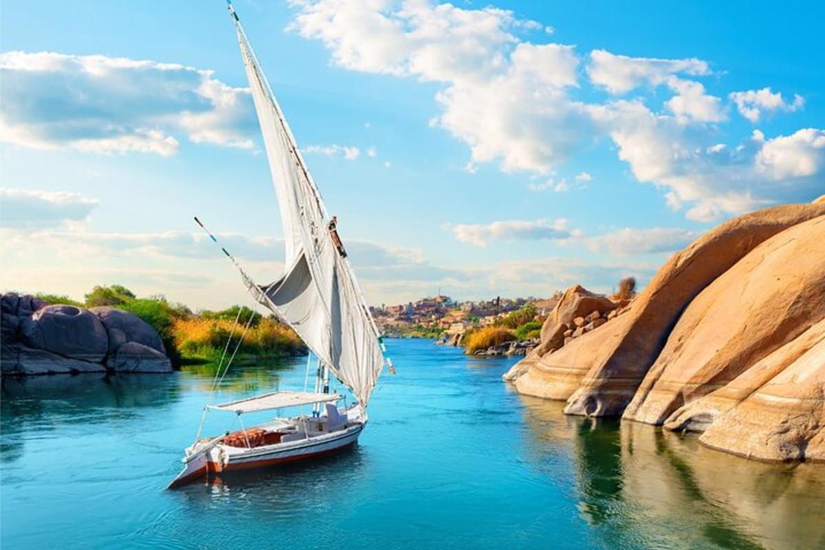 ein Boot mit einem weißen Segel auf einem Fluss