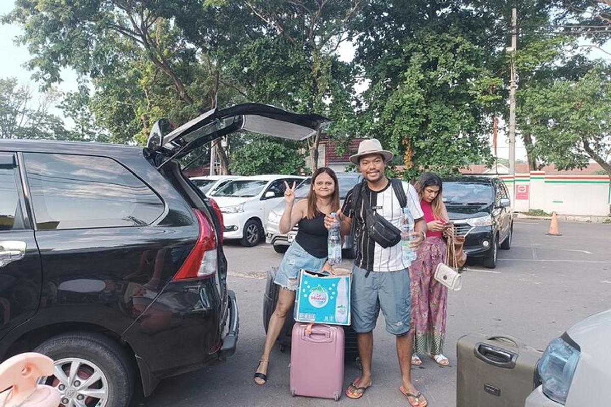 a man and two women standing in front of a car