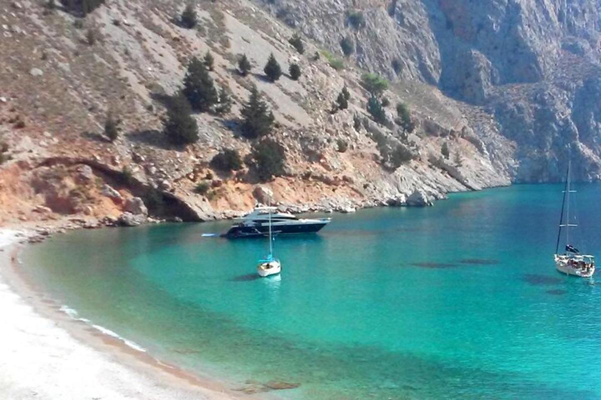 три човни стоять у воді біля гори