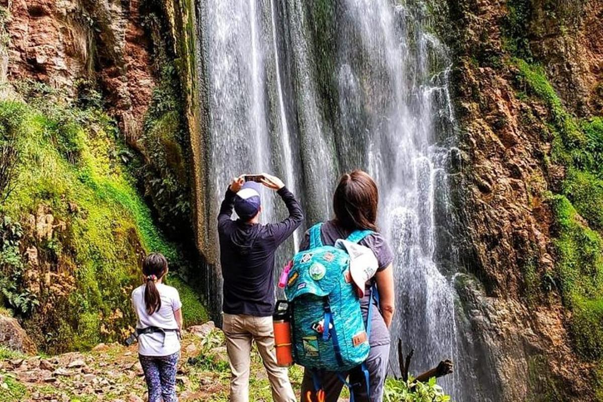 un gruppo di persone in piedi davanti a una cascata