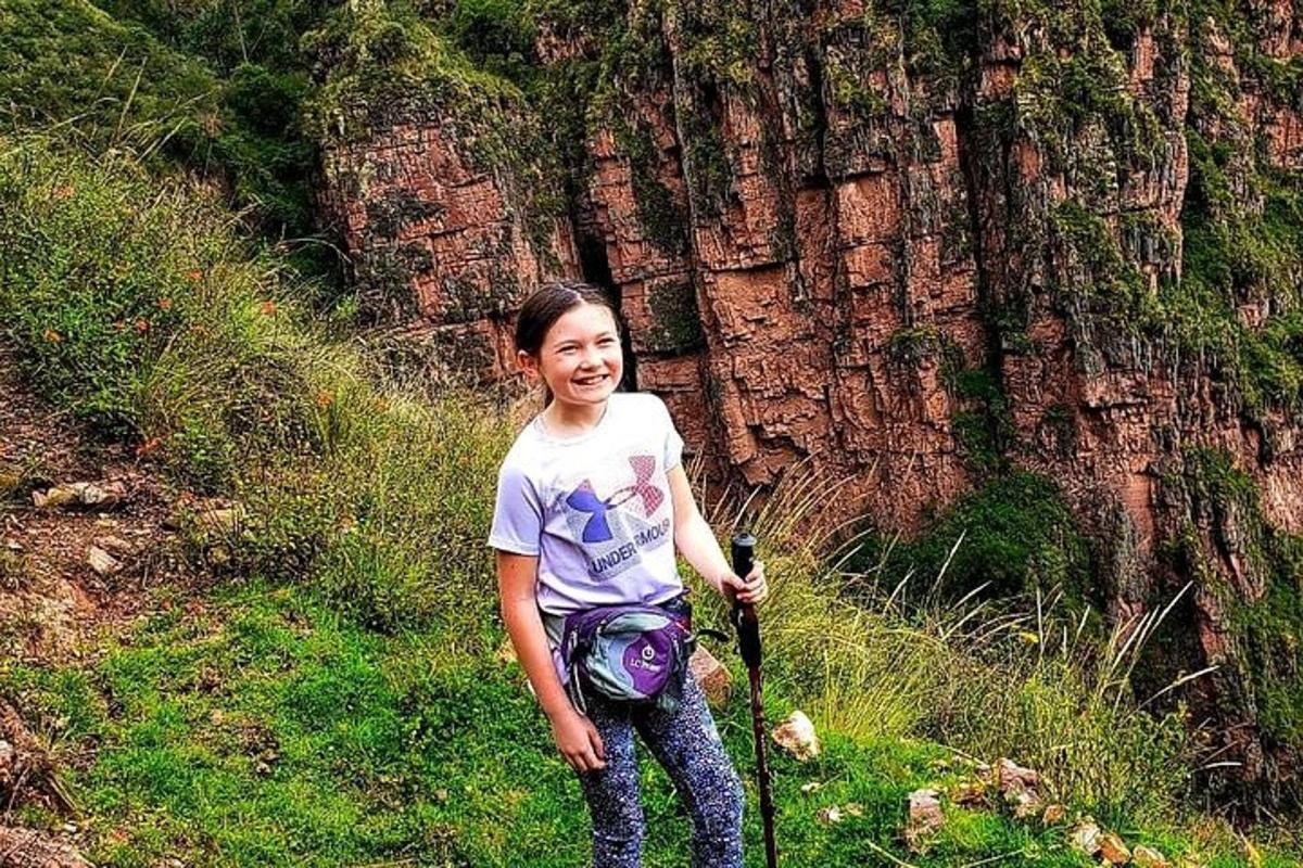 una giovane ragazza in piedi nell'erba vicino a un albero