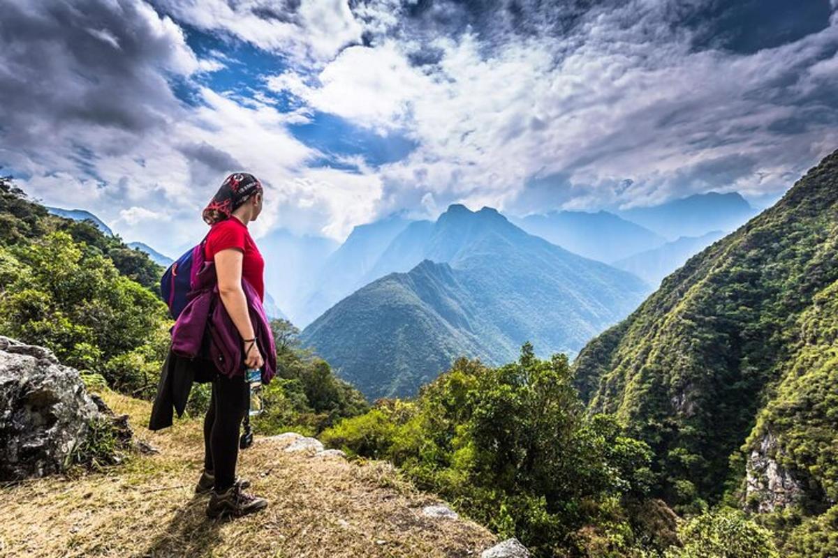 uma mulher parada em uma colina olhando para as montanhas