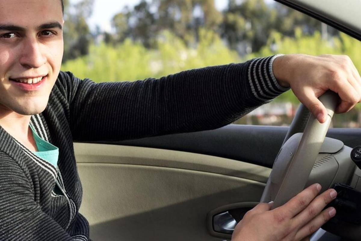 un uomo seduto in macchina che tiene in mano un volante
