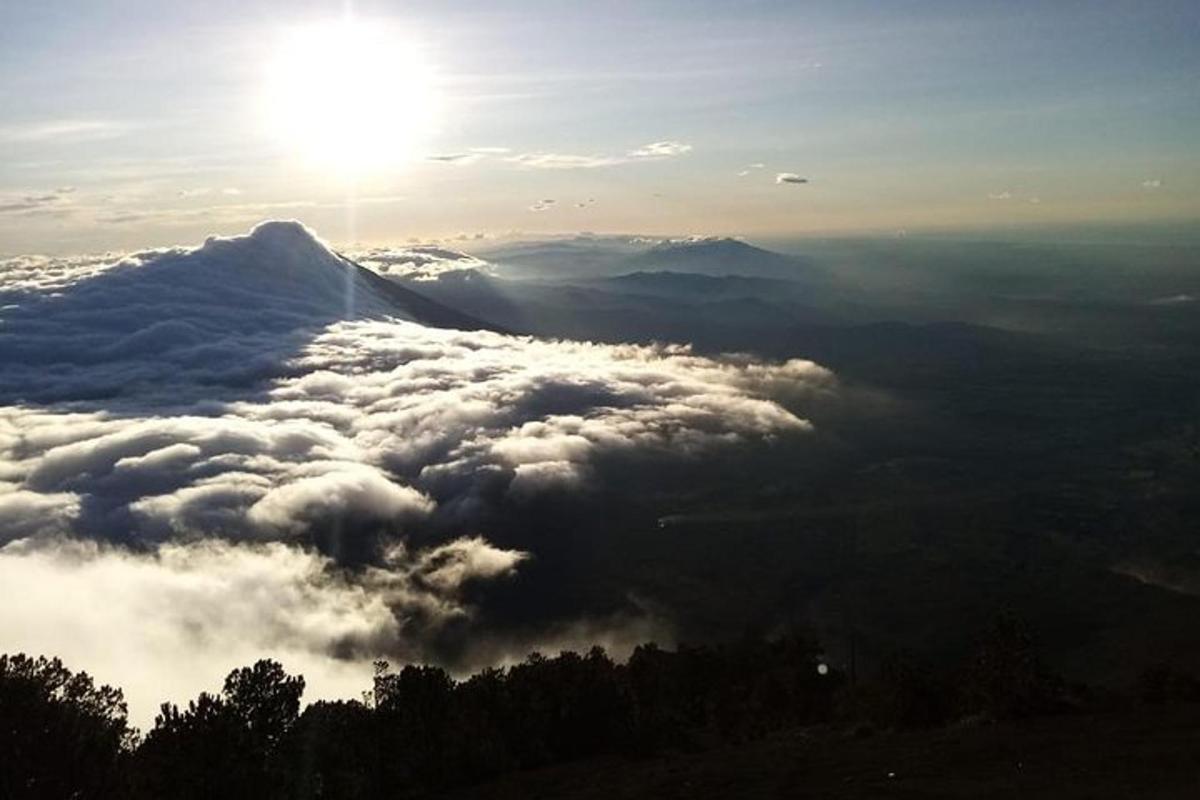 太阳高悬云层之上的山景