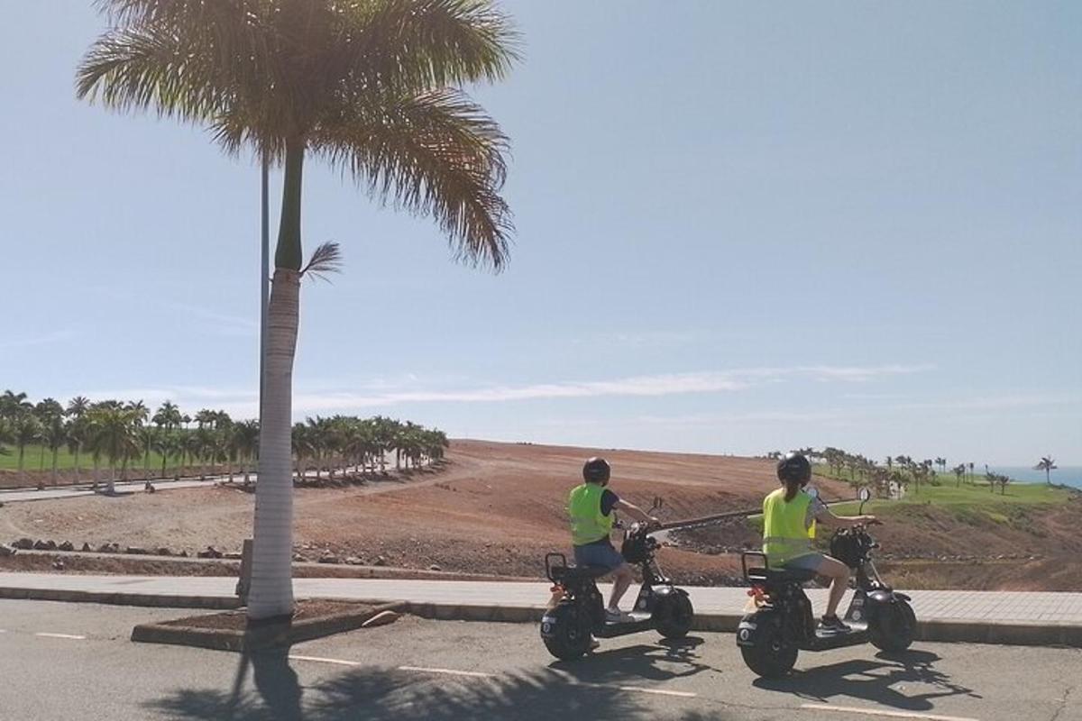 een paar mensen op motoren bij een palmboom