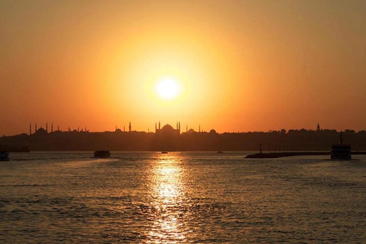 a sunset over the water with a city in the background