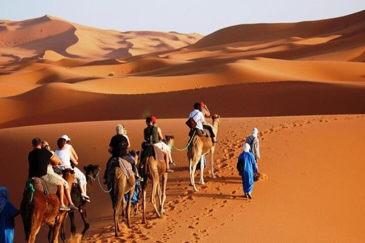 um grupo de pessoas andando de camelo no deserto