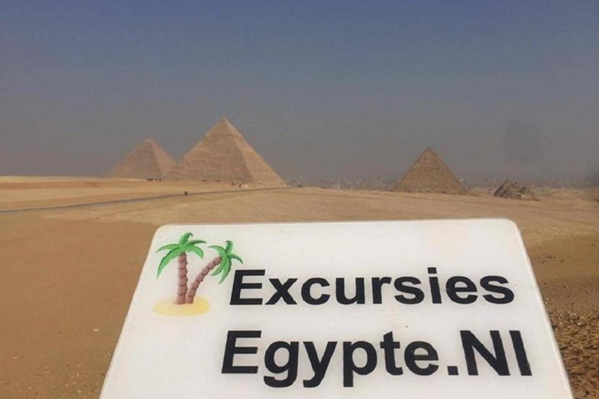 a sign in the desert with the pyramids in the background