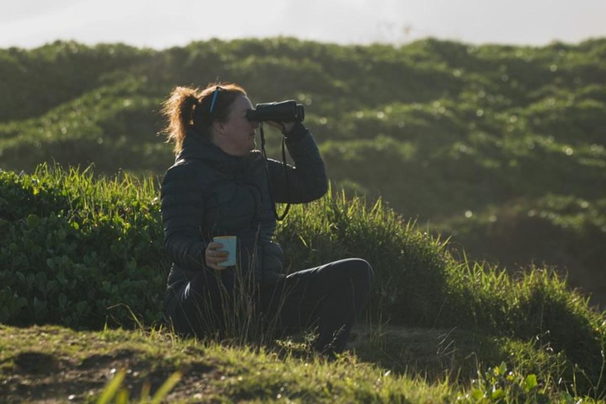 a woman sitting in the grass taking a picture with a camera
