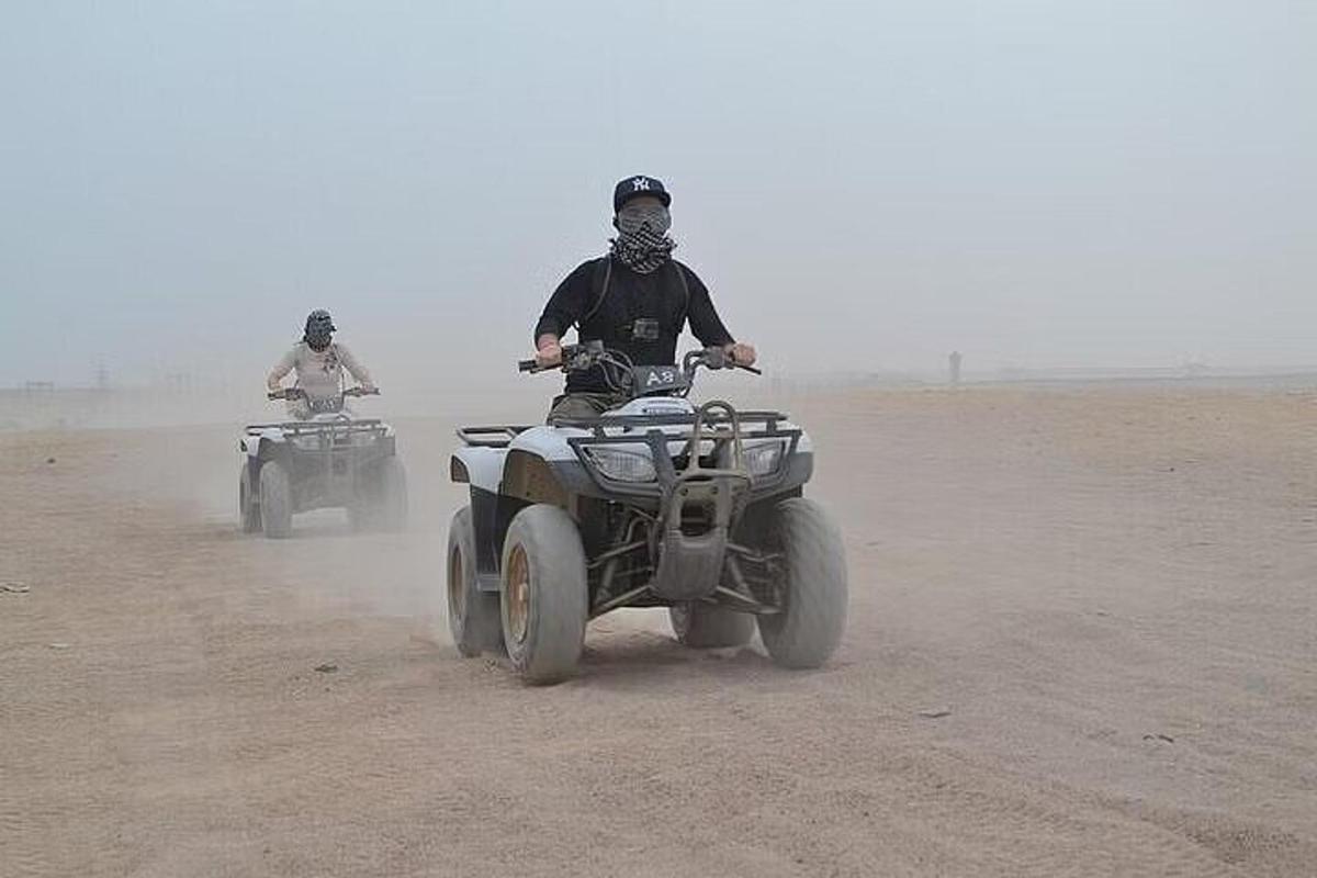 due uomini che guidano quad nel deserto, nella polvere