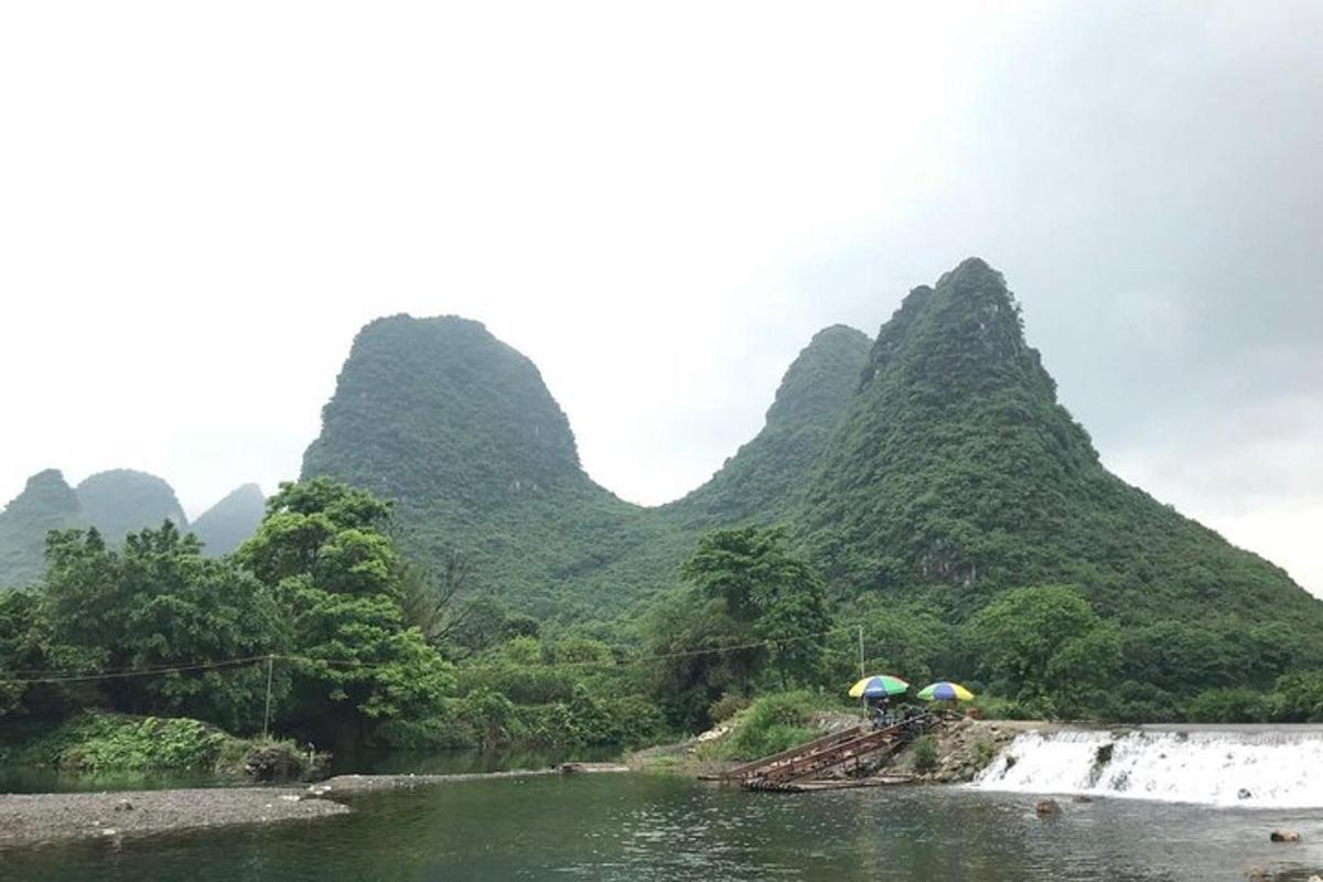 một nhóm người cầm ô trên một dòng sông có núi