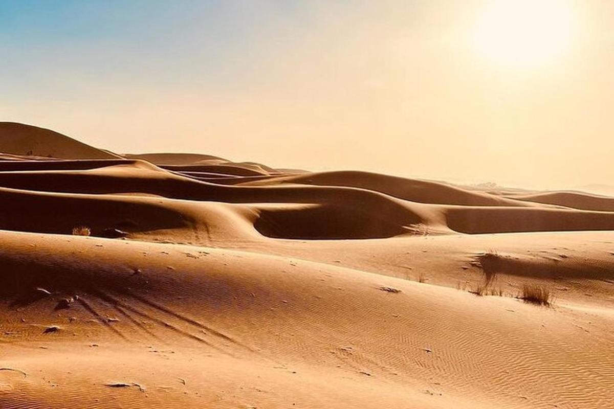 a desert with the sun shining over the sand dunes