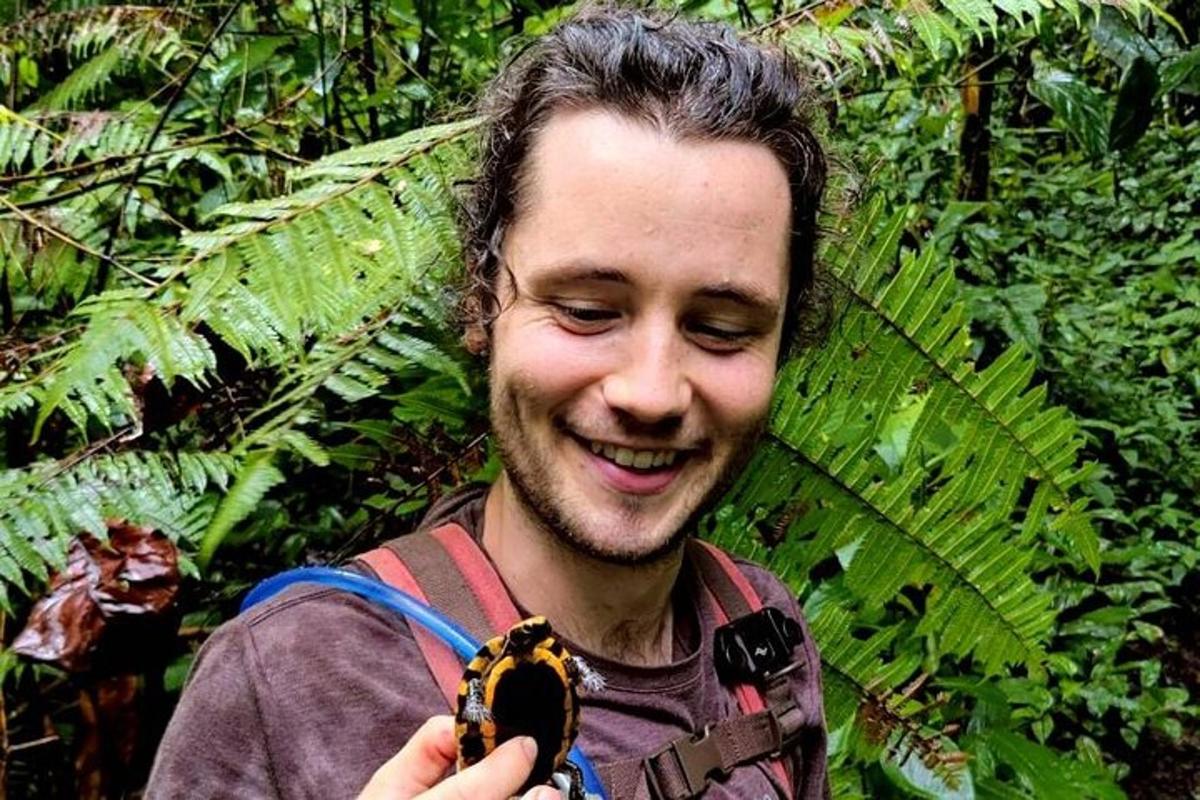un uomo che tiene in mano uno scarabeo in una foresta