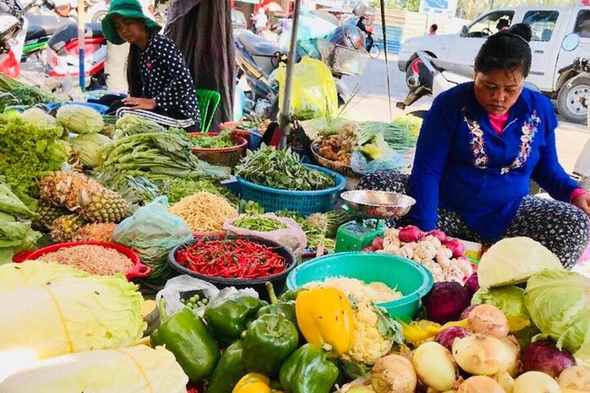 una donna seduta davanti a un mercato con le verdure