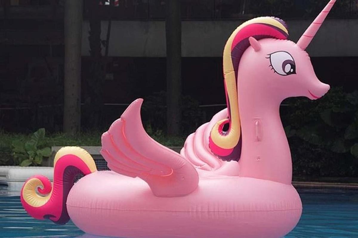 Un unicornio rosa flota en el agua de una piscina.
