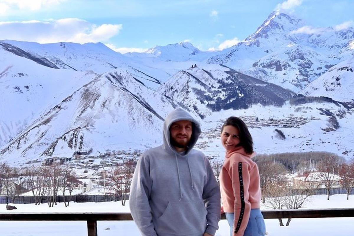 a man and woman standing in front of a snow covered mountain