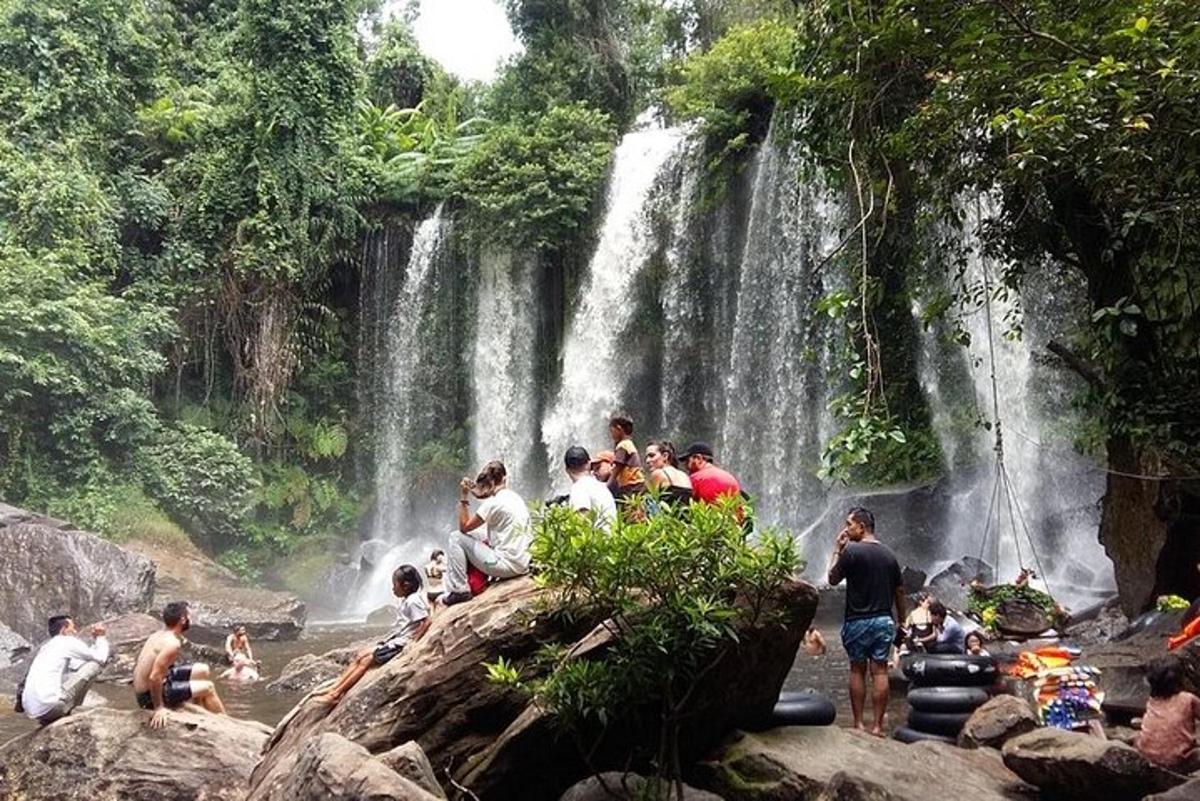un grup de persones assegudes sobre roques davant d'una cascada