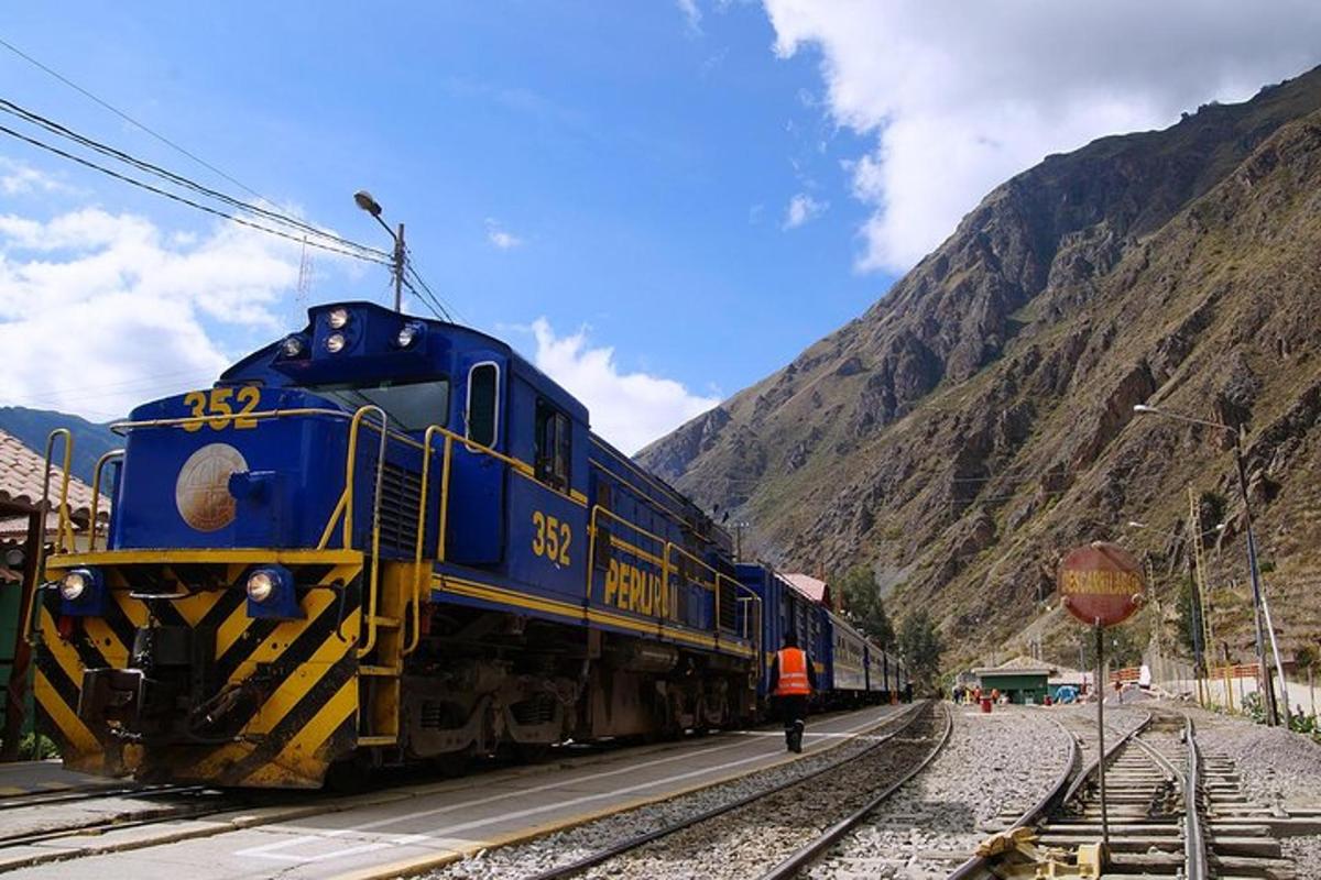 kereta api biru dan kuning di landasan berhampiran gunung
