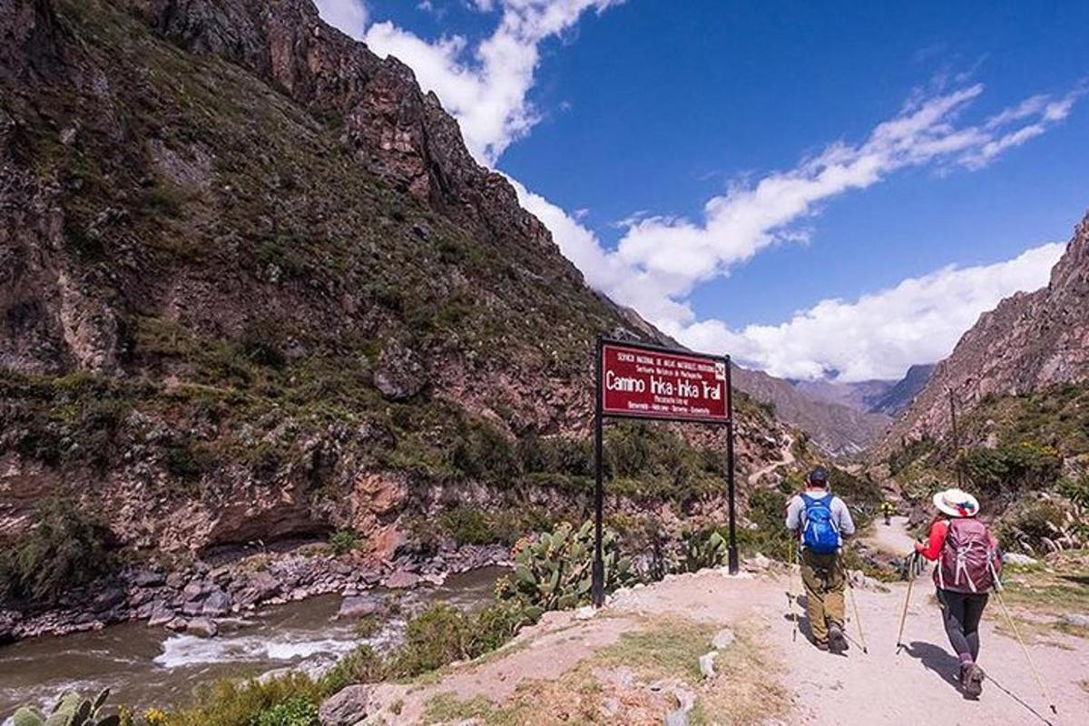 due persone che camminano su un sentiero accanto a un cartello