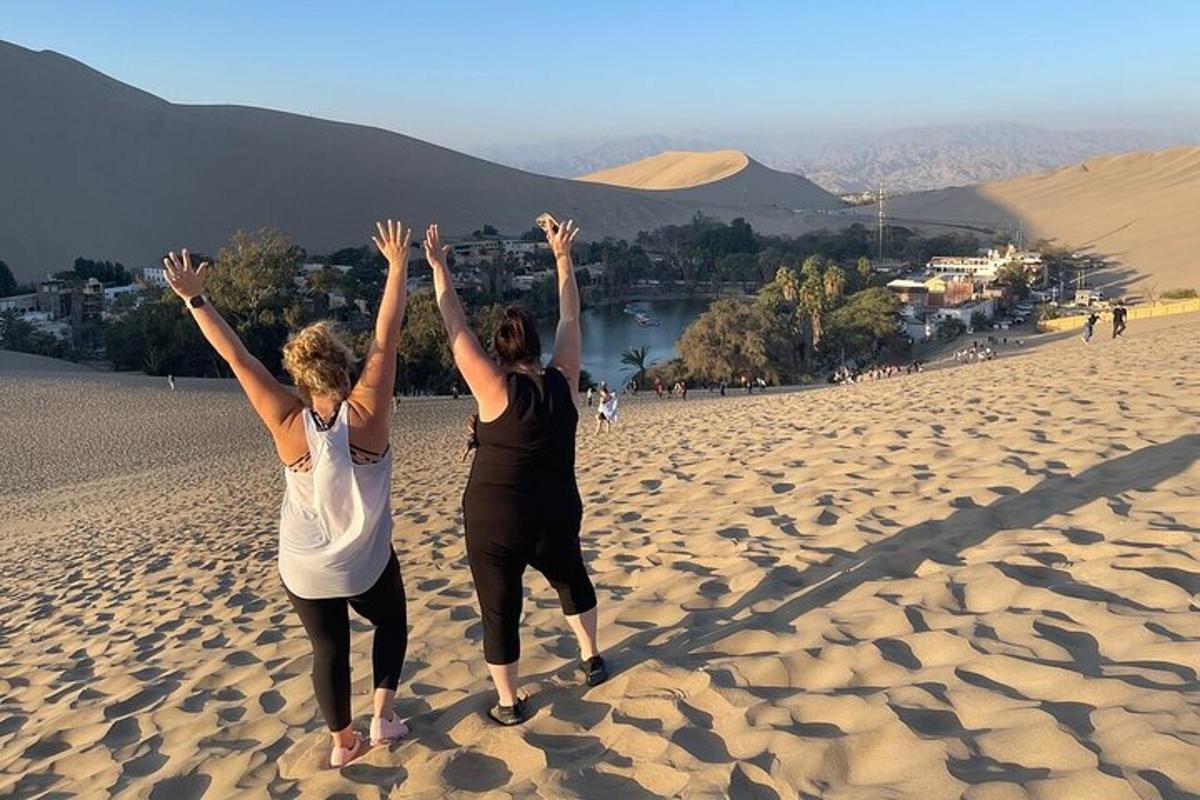 dua wanita berdiri di pantai dengan tangan di udara