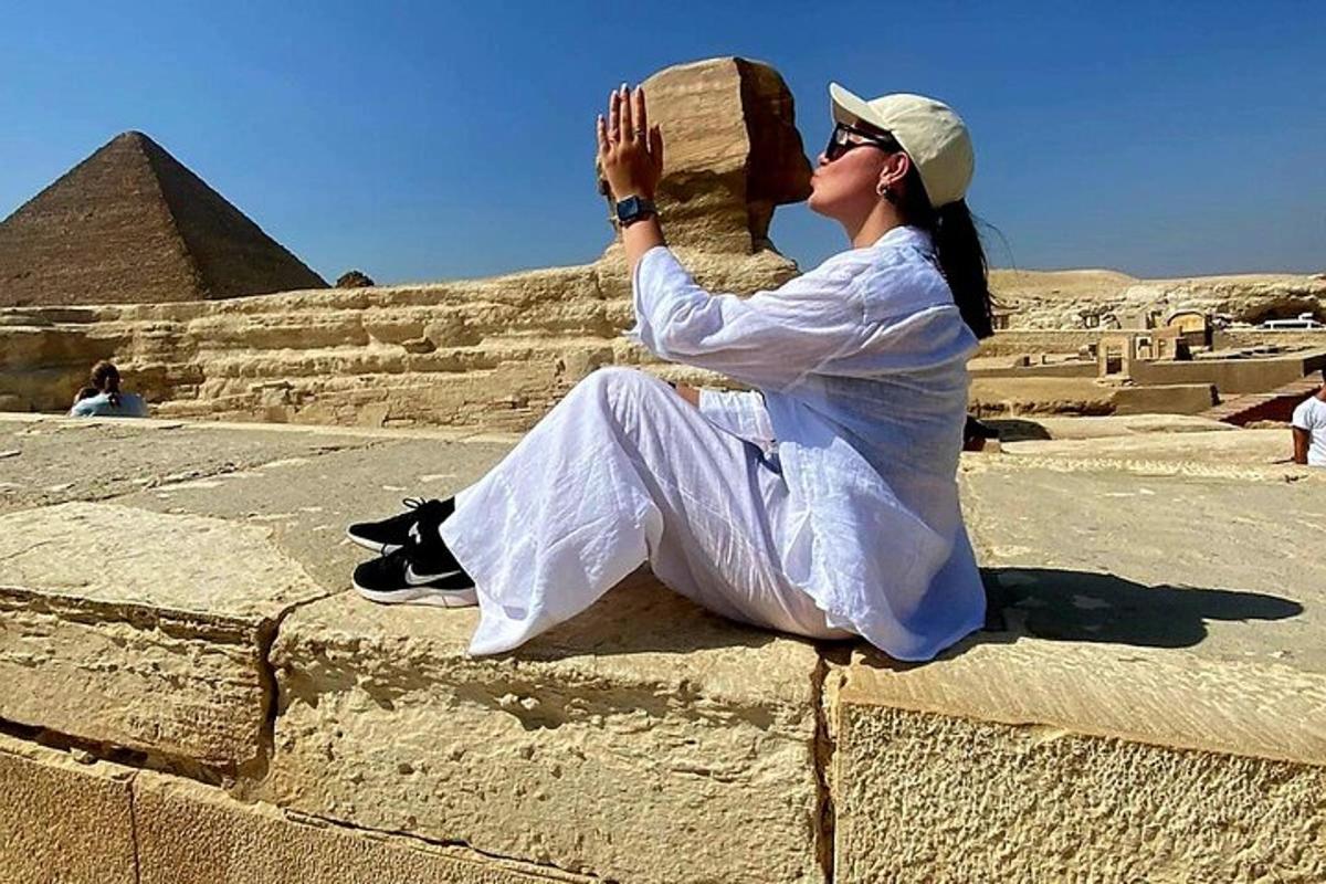 žena sedící na zdi a dívající se na pyramidy