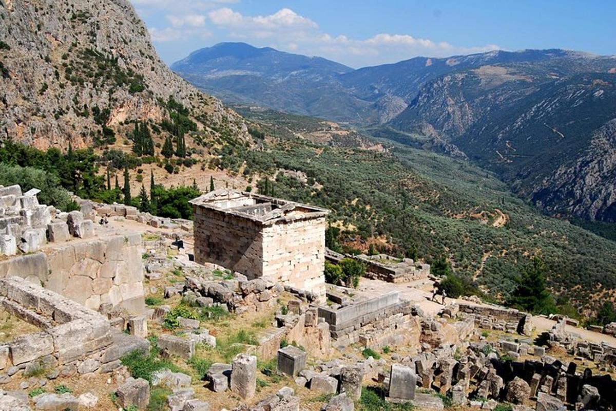 Un edificio antiguo en una colina con montañas al fondo.