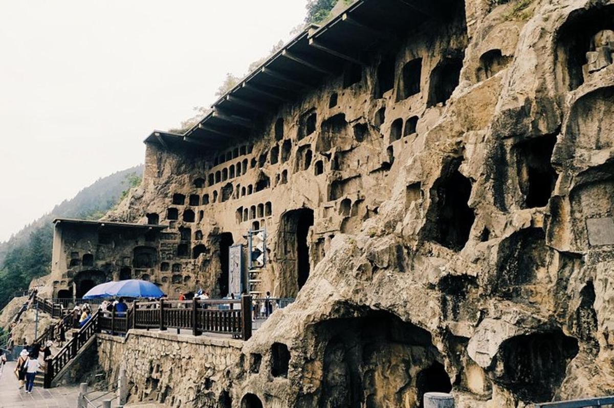 a rock wall with people standing next to a building