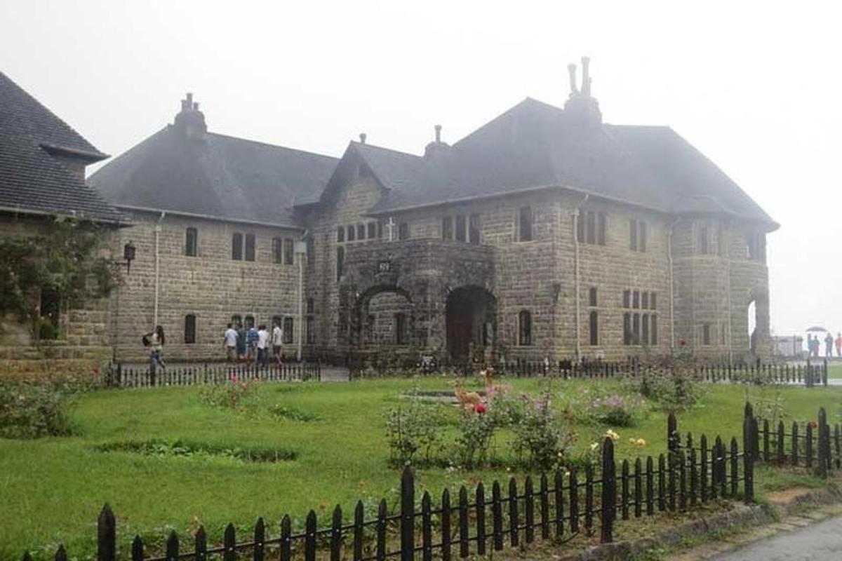 a large stone house with a fence in front of it