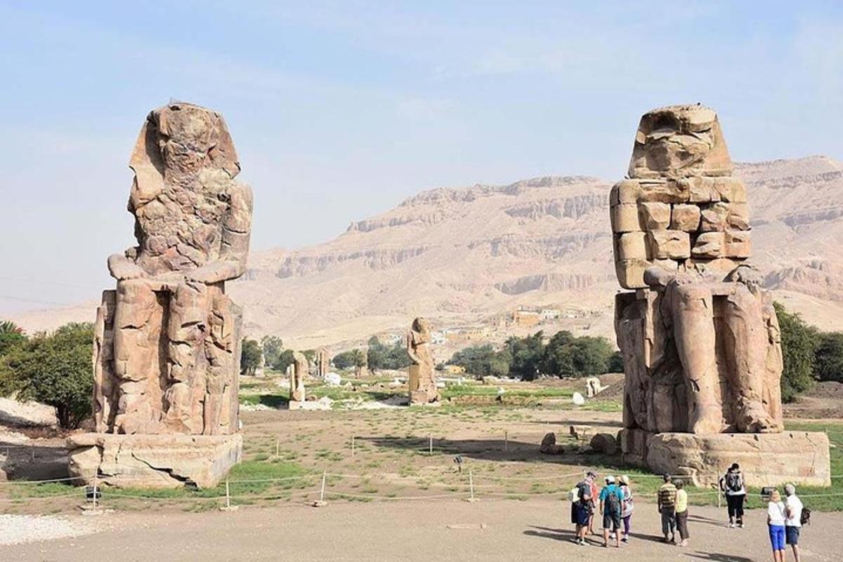 um grupo de pessoas em pé perto de duas grandes estátuas de pedra