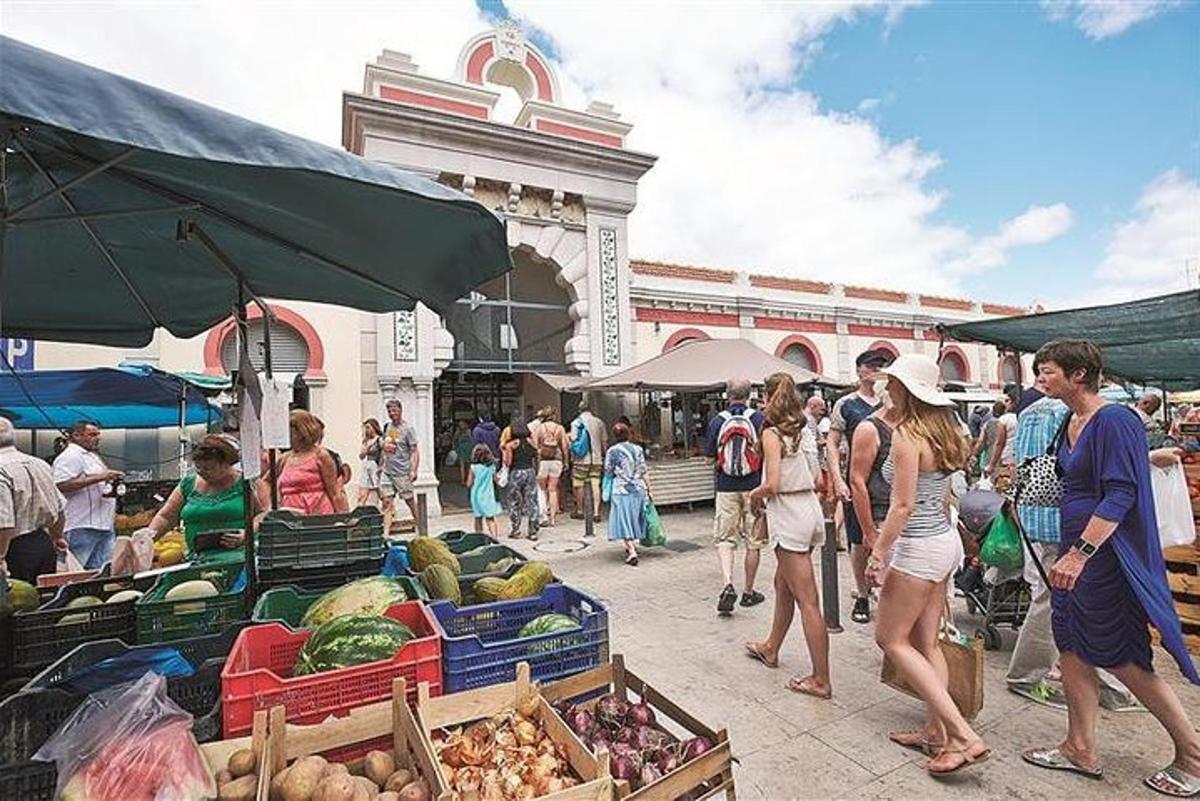 un gruppo di persone che camminano in un mercato all'aperto