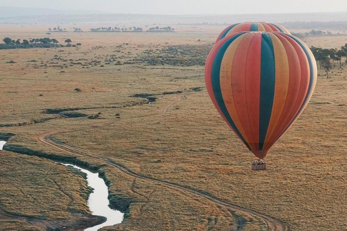 a hot air balloon flying over a river