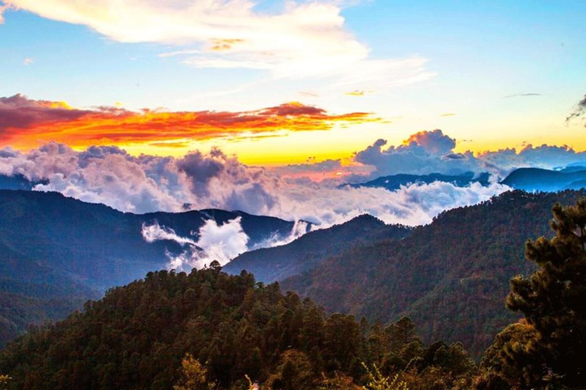 matahari terbenam di atas pegunungan dengan awan di langit