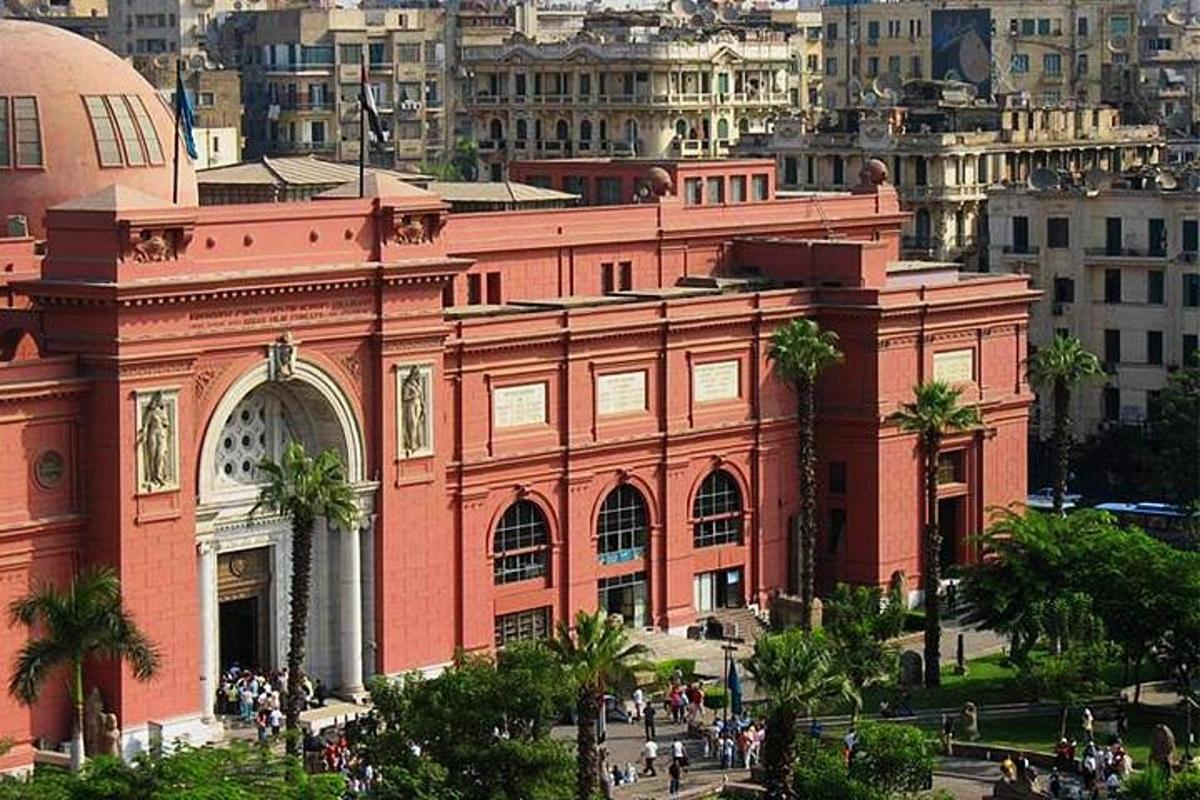 مبنى أحمر كبير به أشجار نخيل أمام مدينة