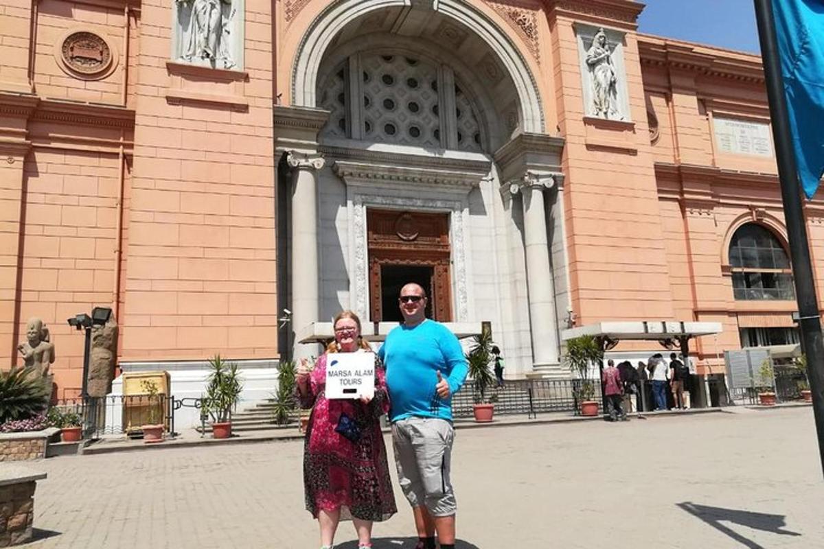 un home i una dona sostenint un cartell davant d'un edifici
