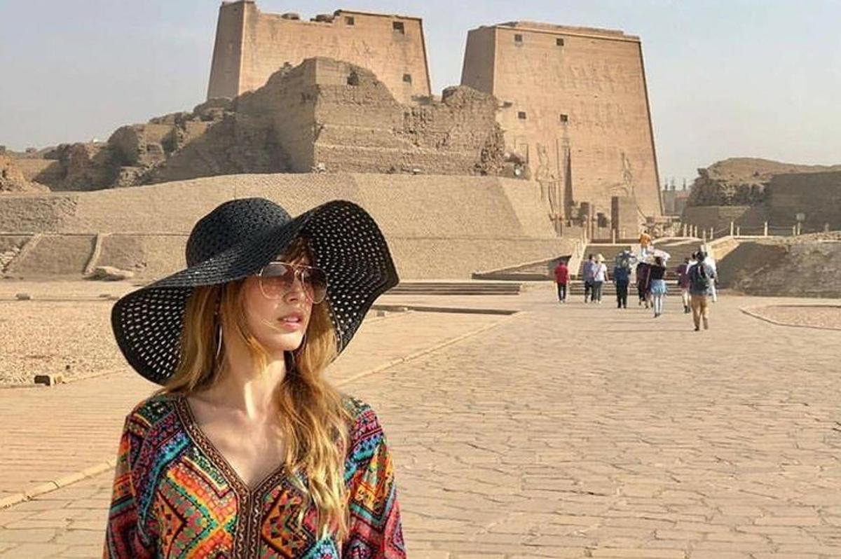 žena v klobouku stojící před pyramidou