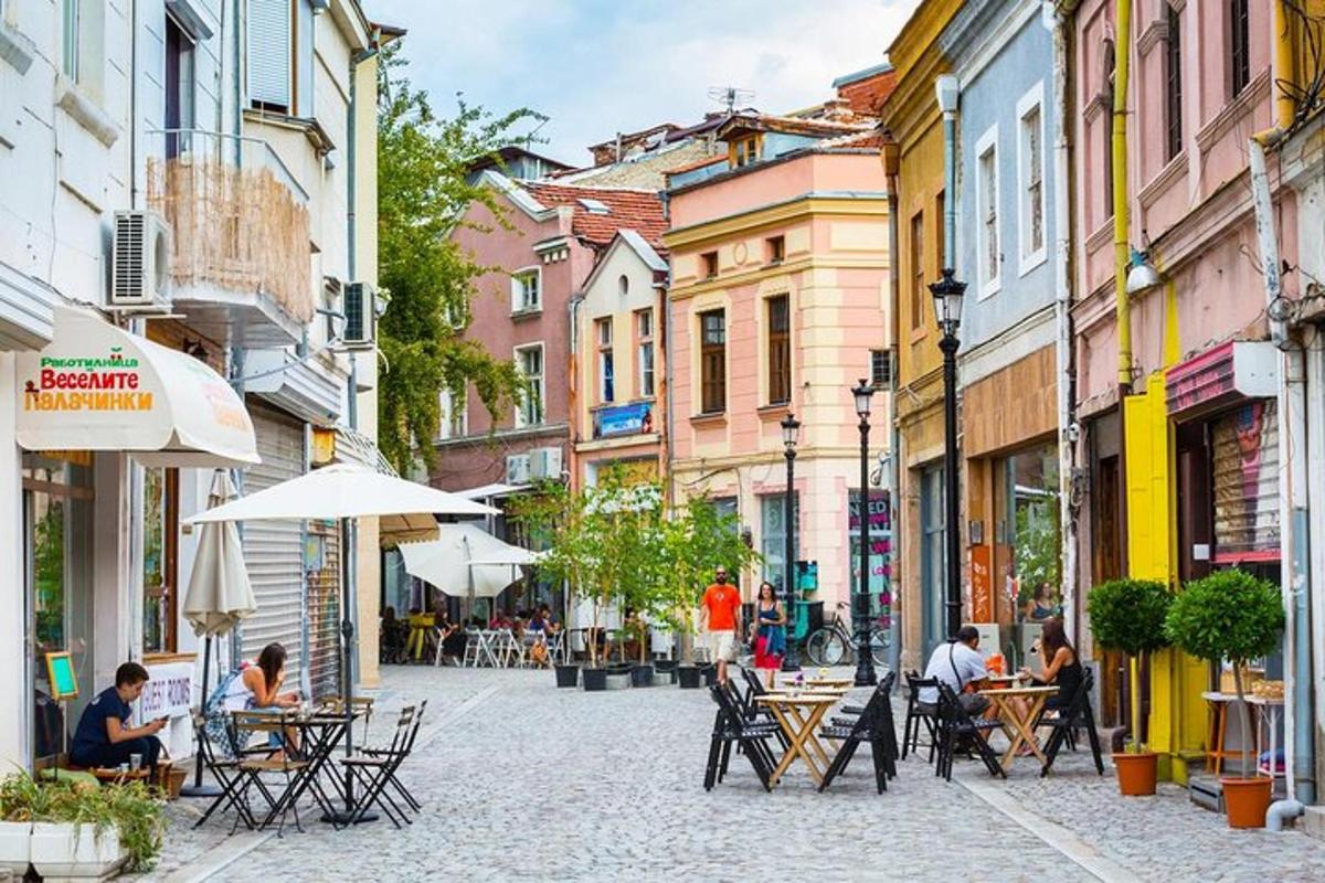 ulice se stoly a židlemi a lidmi sedícími u stolů
