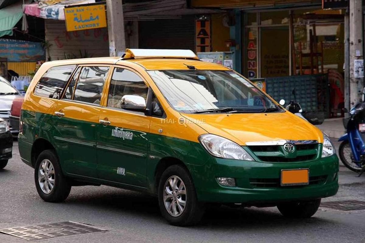 sebuah kereta kecil berwarna hijau dan kuning memandu di sebatang jalan