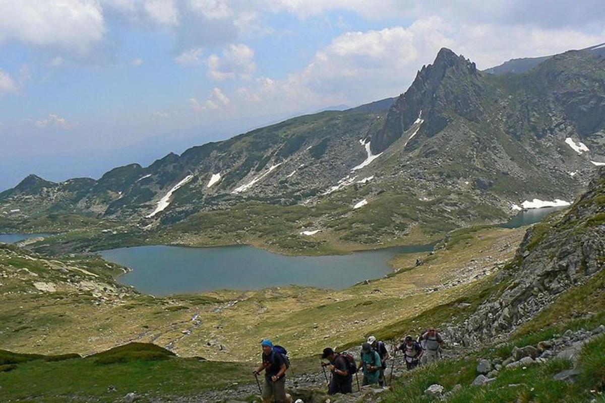 a group of people walking up a mountain with a lake