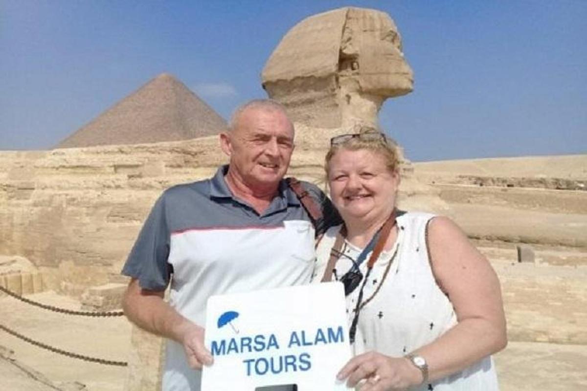 mies ja nainen pitelevät kylttiä pyramidien edessä