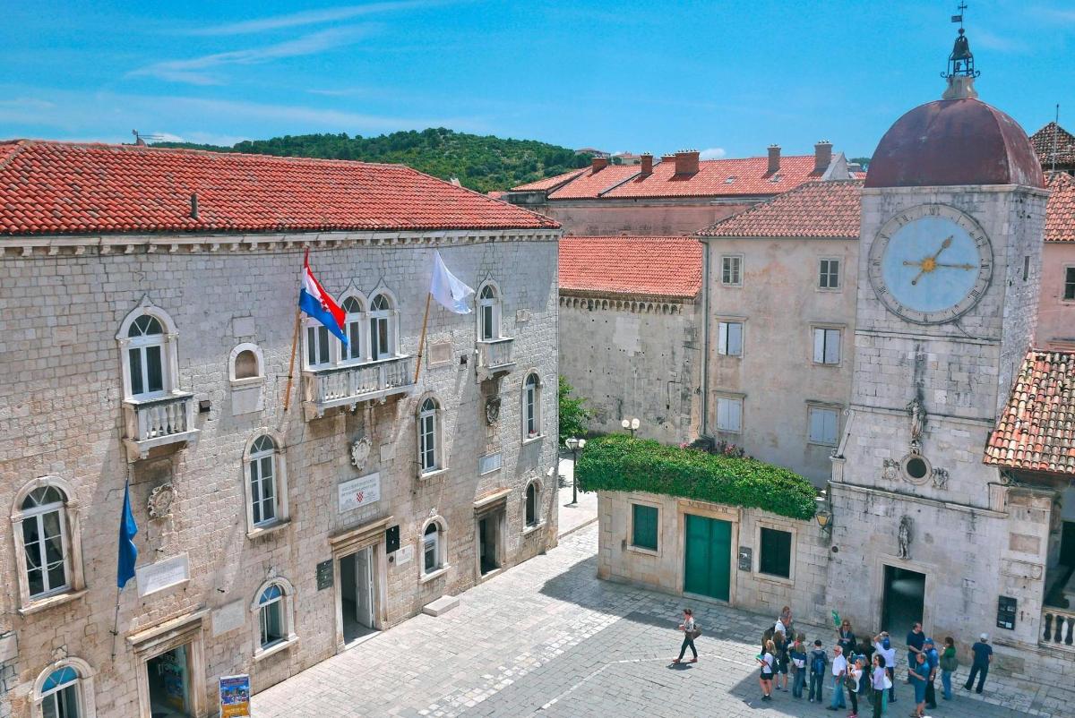 група људи која шета градом са сат-кулом