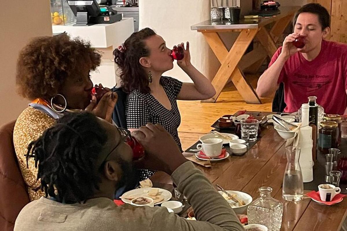 un grup de persones assegudes al voltant d'una taula bevent vi