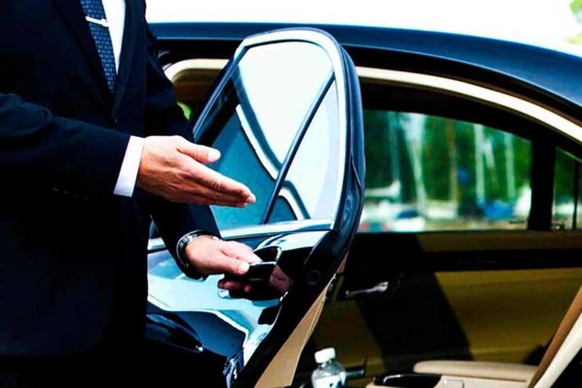 Ένας άντρας με κοστούμι ανοίγει την πόρτα ενός αυτοκινήτου