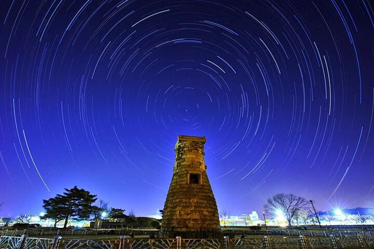 a clock tower with star trails in the sky