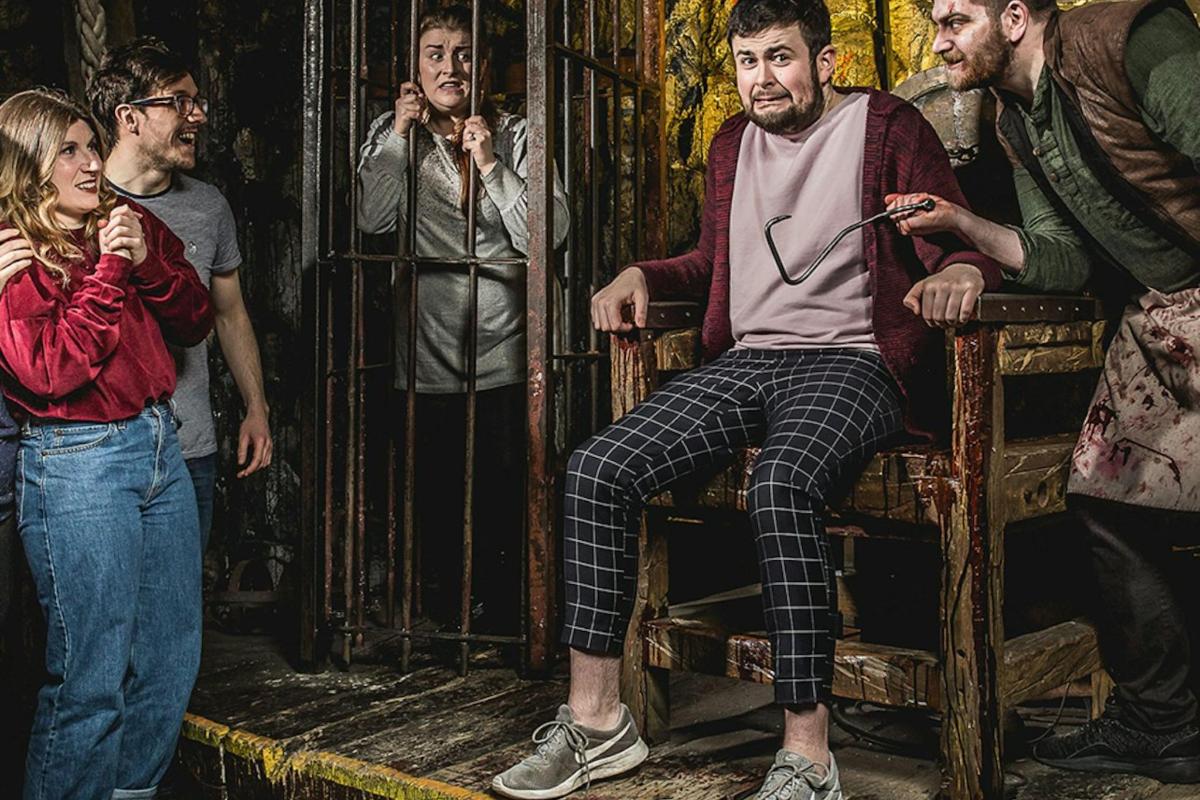 cilvēku grupa, kas stāv ap vīrieti būrī